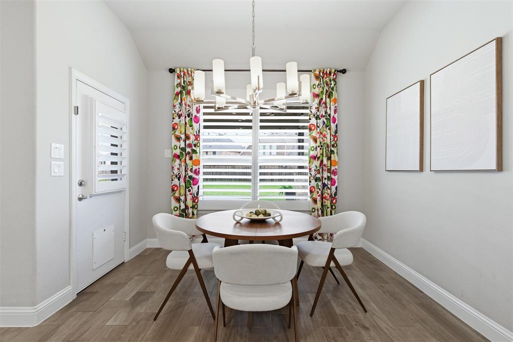 Dining area featuring wood-finish flooring, a contemporary chandelier, and a window with plantation shutters