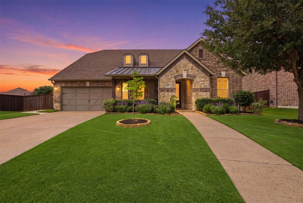 Traditional-style residence featuring a brick and stone facade, arched entryway, and a prominent two-car garage