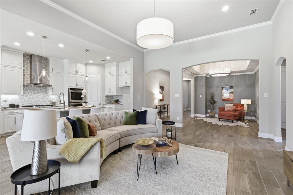 Open-concept living space with wood-finish flooring, a white kitchen, and an arched entryway