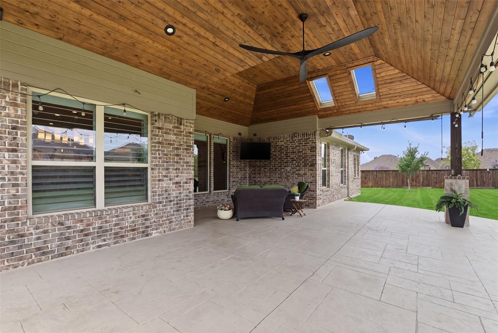 This stunning patio features a vaulted tongue-and-groove cedar ceiling with skylights, oversized modern fan, recessed lighting