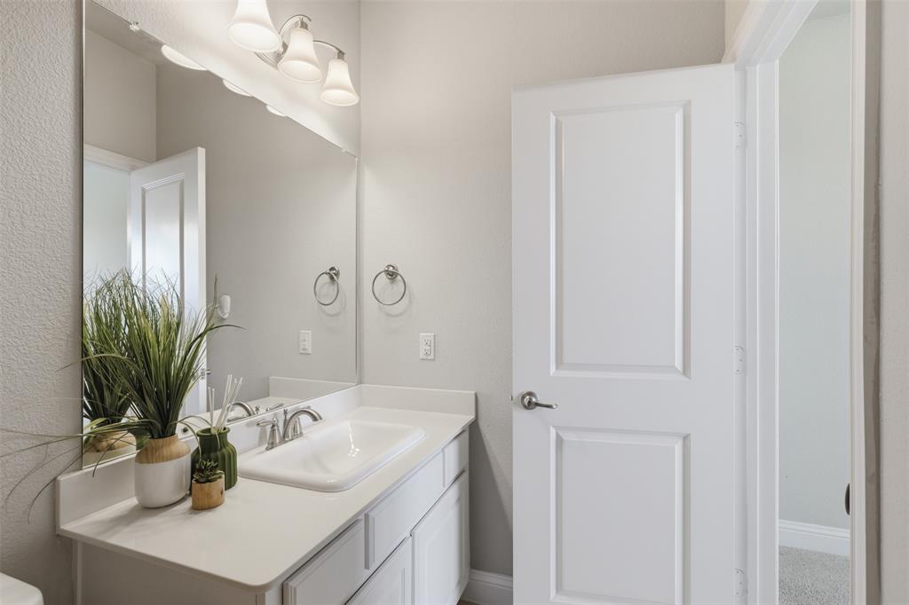 Bathroom vanity featuring a white countertop with an integrated sink, brushed nickel faucet, and a large wall-mounted mirror