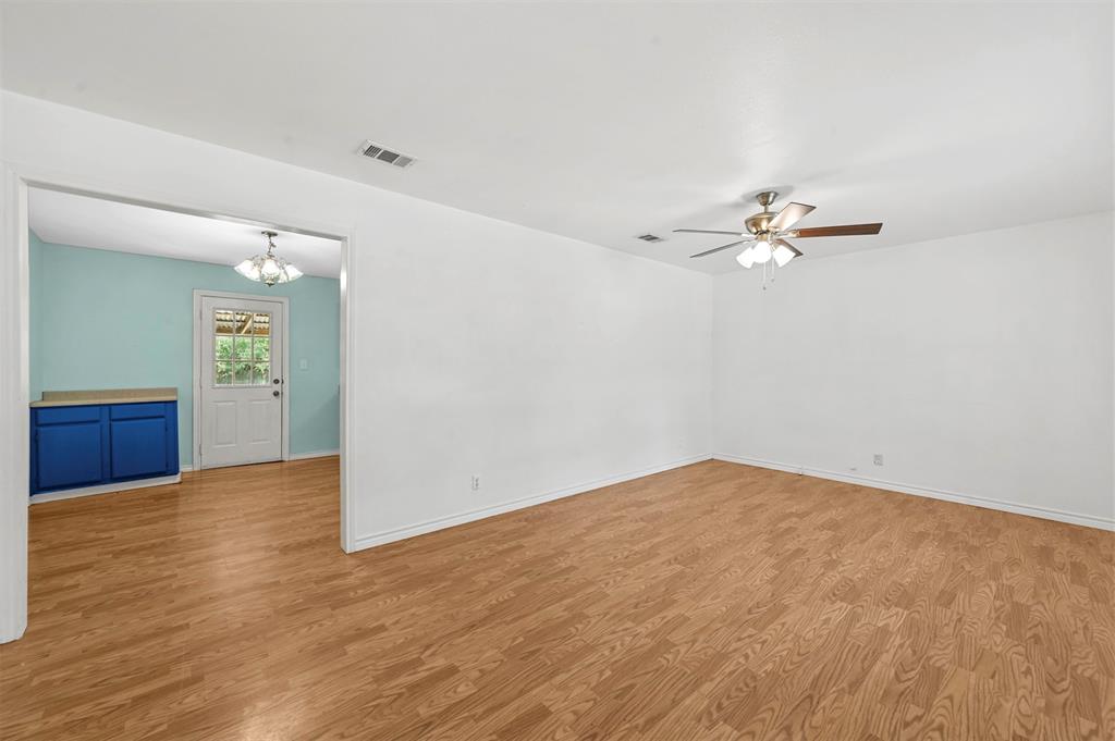 Unfurnished room with ceiling fan with notable chandelier and light hardwood / wood-style floors