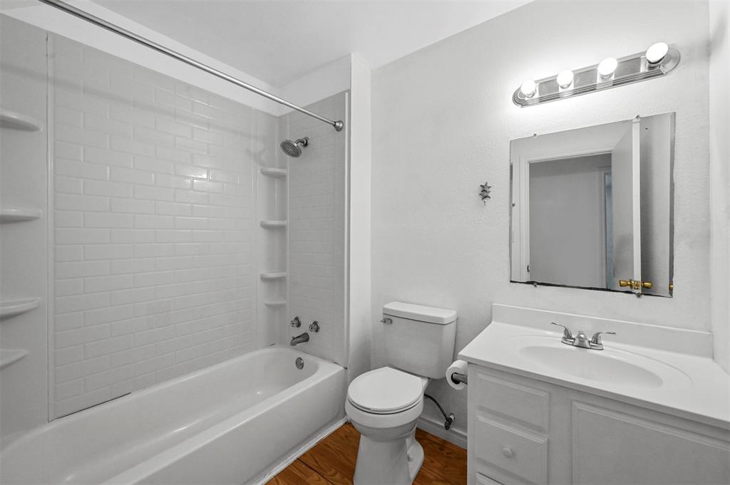 Full bathroom with vanity, toilet, hardwood / wood-style floors, and tiled shower / bath