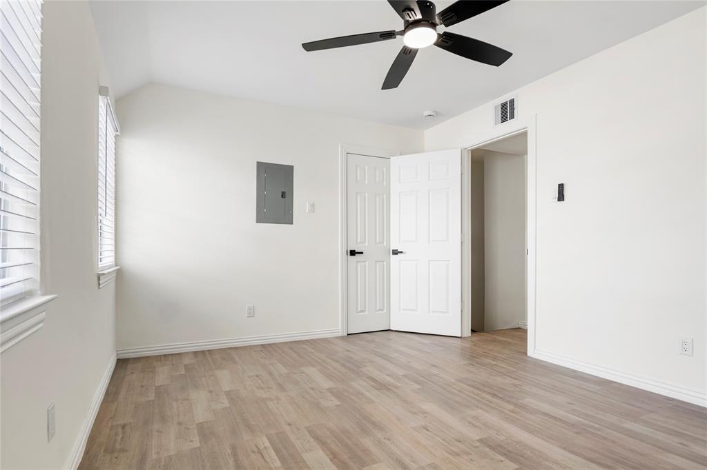 Room featuring light wood-finish flooring, white painted walls, and a black ceiling fan with integrated lighting