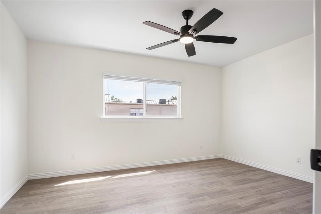 Bright room featuring a window with white blinds, wood-finish flooring, a ceiling fan with integrated lighting, white walls, and white trim