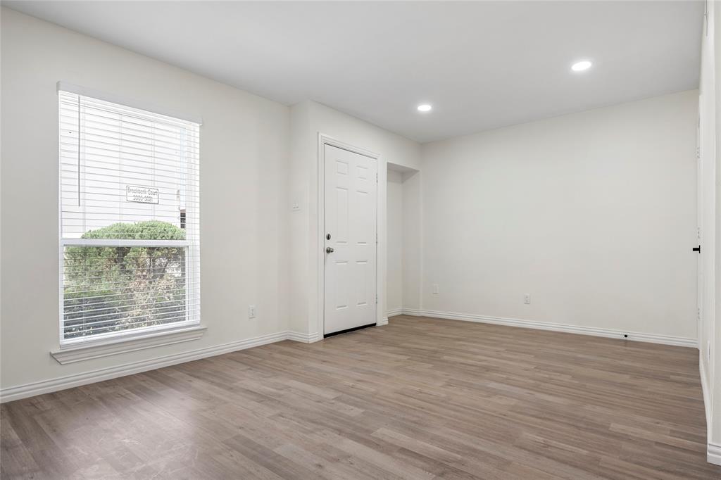 Spacious room featuring wood-finish flooring, white walls, and recessed lighting