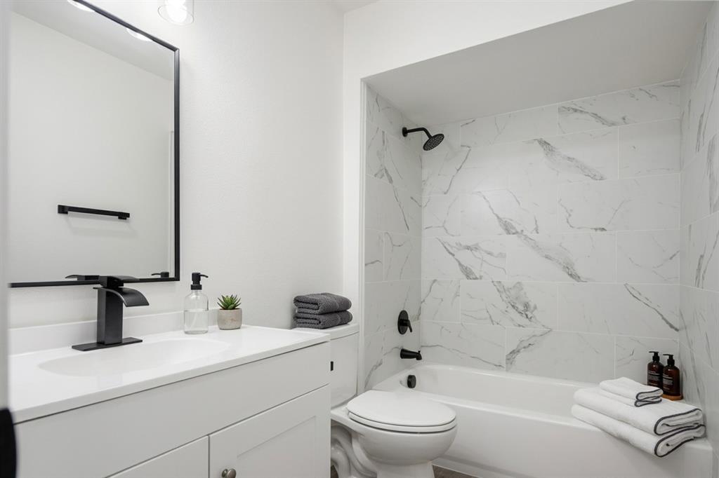 White single vanity with a solid surface countertop, matte black faucet, and rectangular mirror