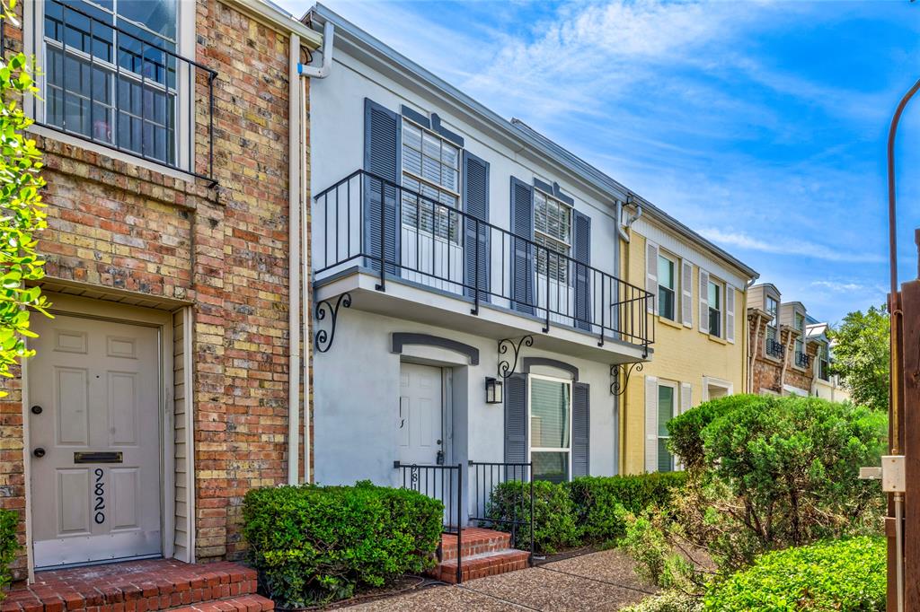 White stucco exterior with a second-story balcony featuring wrought iron railings