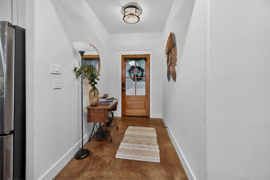 Entryway featuring warm-toned flooring, a light wood door with glass panes, and a contemporary ceiling light fixture