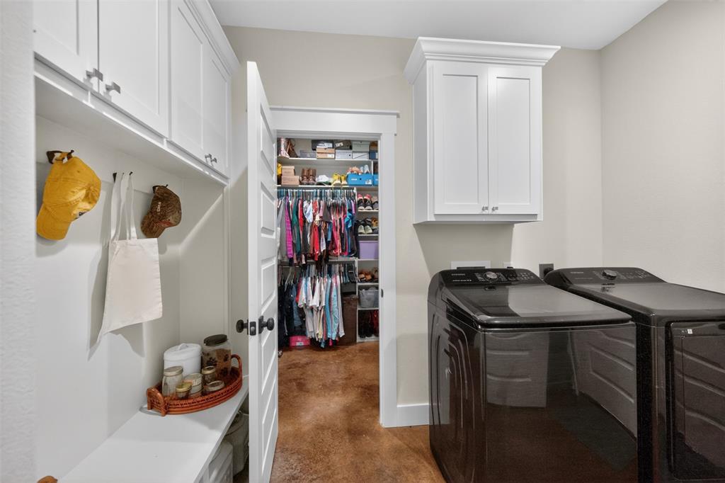 Dedicated utility area featuring white shaker-style cabinetry, a built-in bench with storage, and a deep walk-in closet with custom shelving