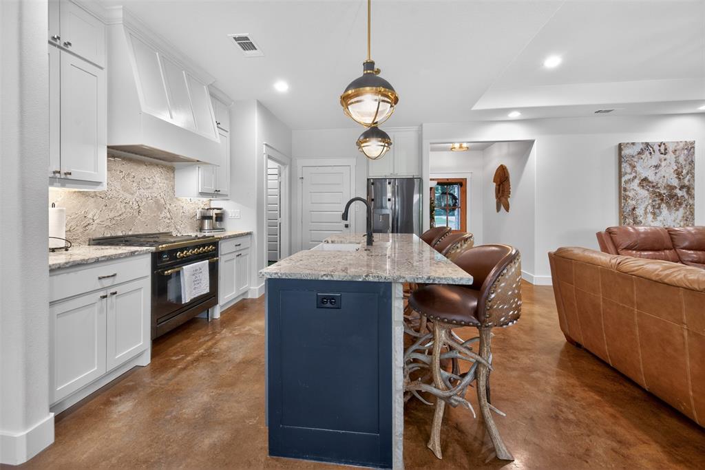 The kitchen features white cabinetry, a dark blue island with a light-colored countertop, and a ILVE high end range