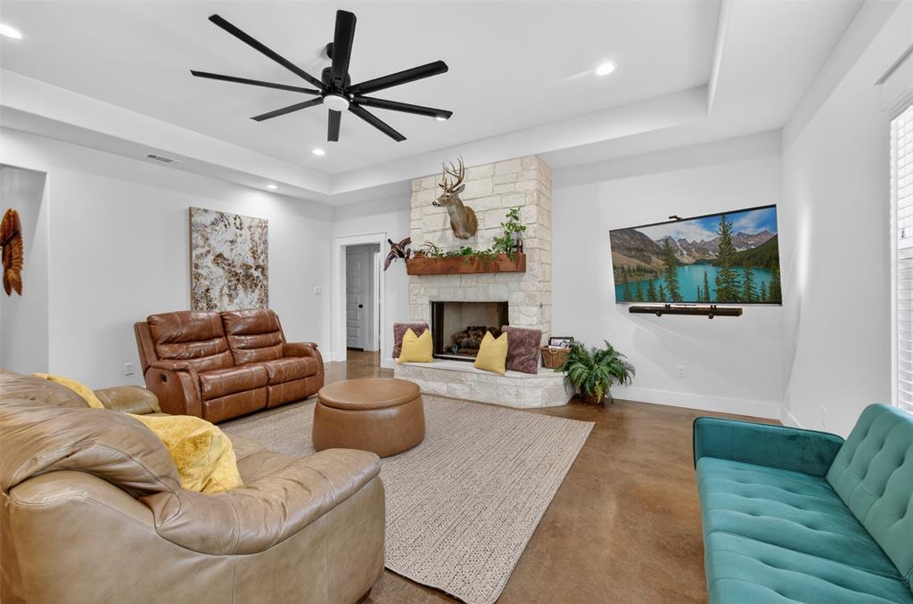 Living area featuring a stone fireplace with a wooden mantel, a large ceiling fan, and recessed lighting