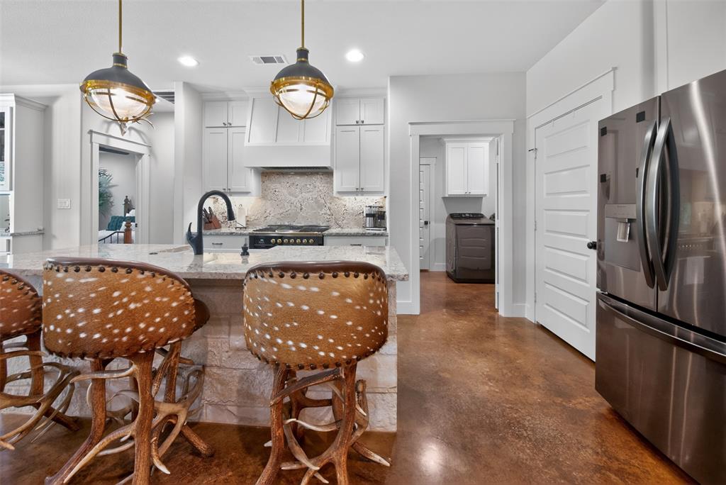 The kitchen features a large island with a granite countertop and a stainless steel sink with a black gooseneck faucet