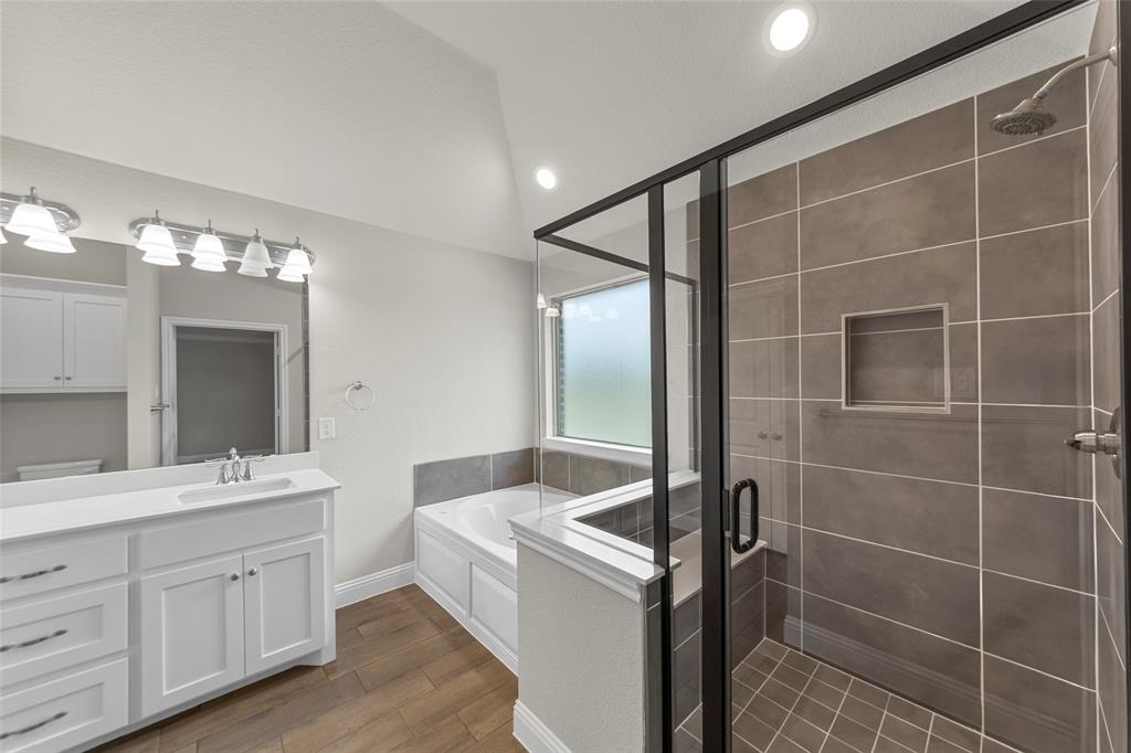 Bathroom featuring a glass-enclosed shower with tiled walls and floor, a built-in shower niche, and a bathtub with a privacy window