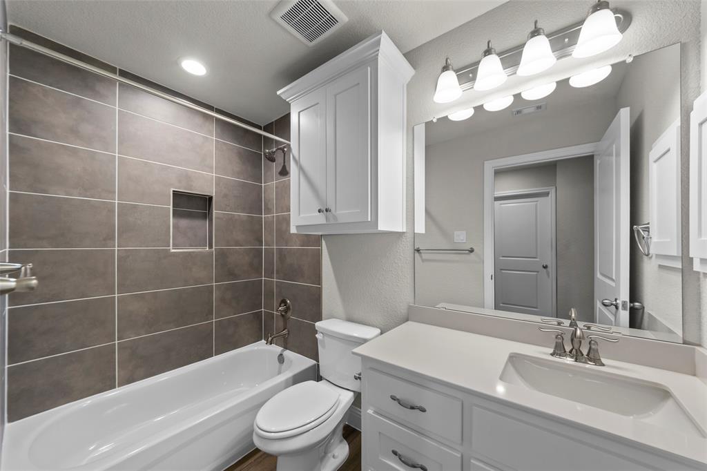 Bathroom featuring a white vanity with an integrated sink and brushed nickel faucet, a large mirror, and a five-light fixture
