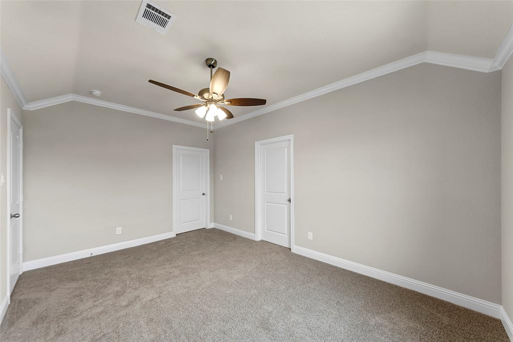 Carpeted room featuring a vaulted ceiling with crown molding, two panel doors, a ceiling fan with light kit, and neutral wall paint
