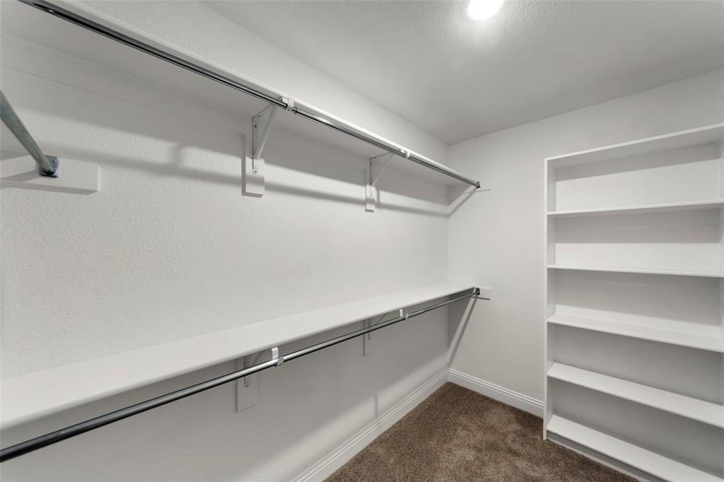 Walk-in closet featuring white walls, chrome hanging rods, and built-in shelving