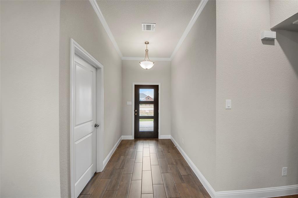 Hallway featuring wood-finish tile flooring, a two-panel interior door, and crown molding