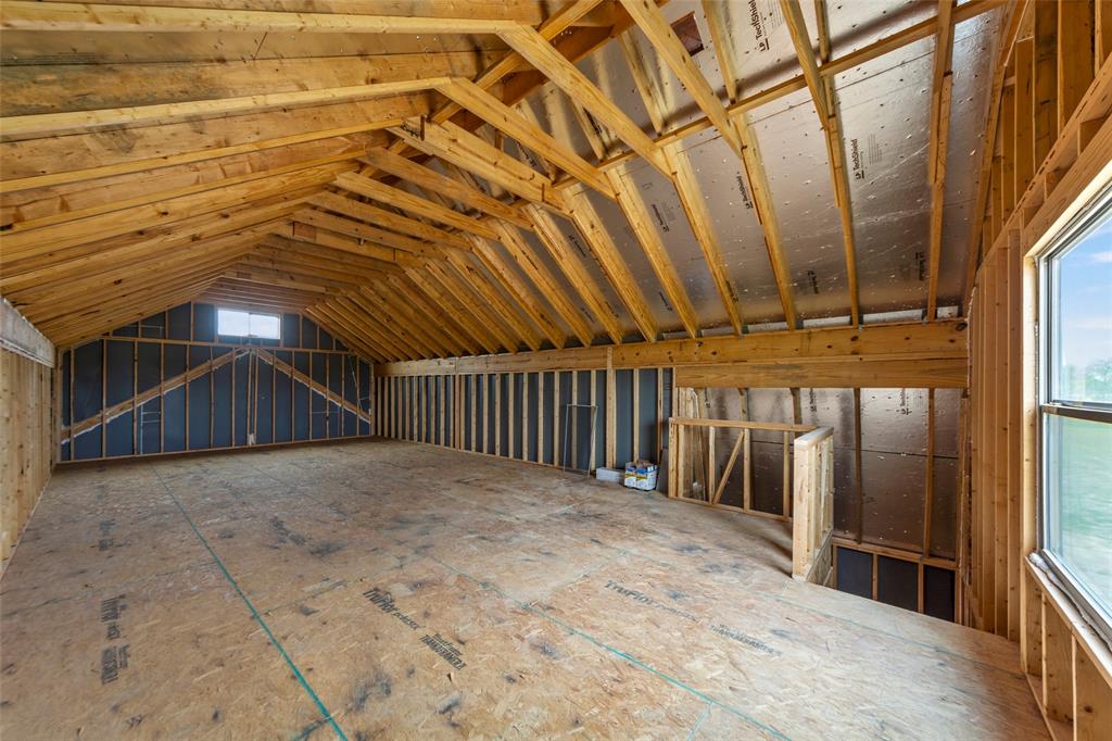 Unfinished bonus room featuring exposed wood framing, a wide window, and a smaller dormer window