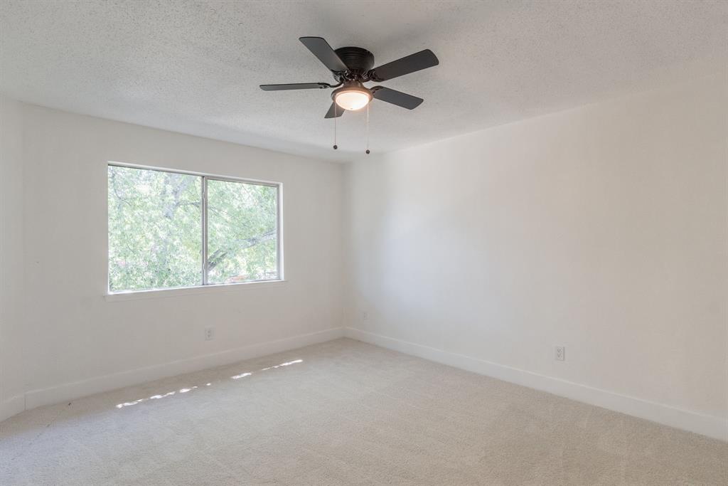 Carpeted room with a ceiling fan and a dual-pane window