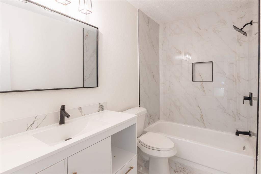 Bathroom featuring a white vanity with integrated sink, black matte faucet, and a large framed mirror