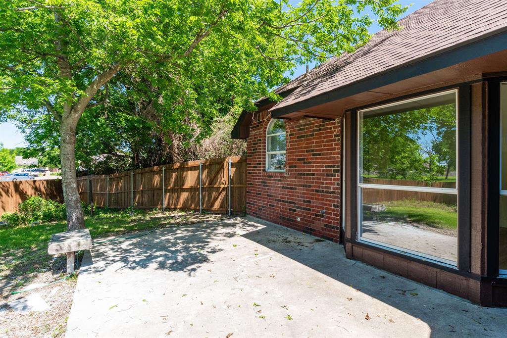 Concrete patio space with a brick exterior, large picture window, and arched window
