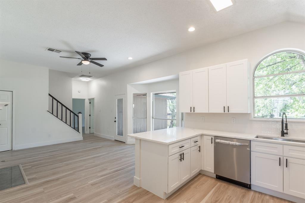 Modern kitchen featuring white shaker cabinetry, stainless steel appliances, and light-tone wood-finish flooring