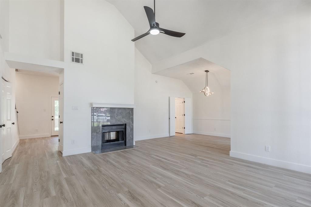 Spacious living area featuring a vaulted ceiling, wood-finish flooring, and a contemporary ceiling fan