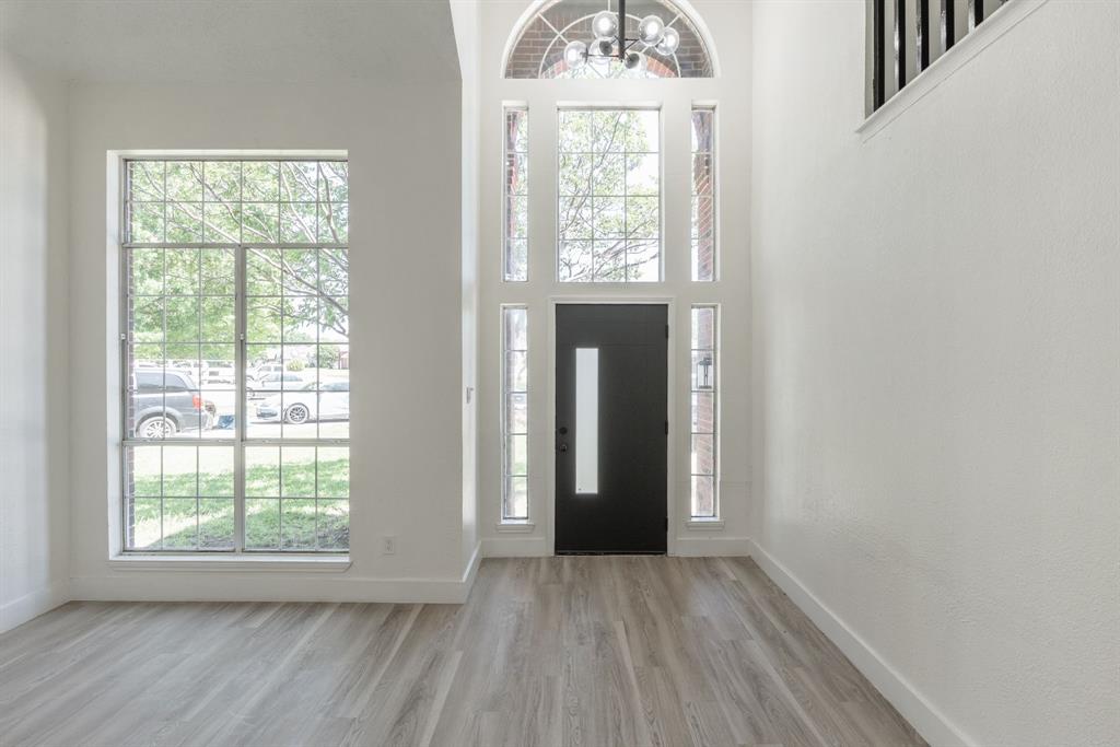 Two-story foyer featuring a black entry door with vertical glass insert, transom window, and side lite windows