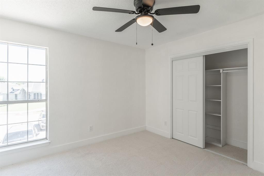 Bright room featuring a ceiling fan with light, plush carpet, and a large window with white trim