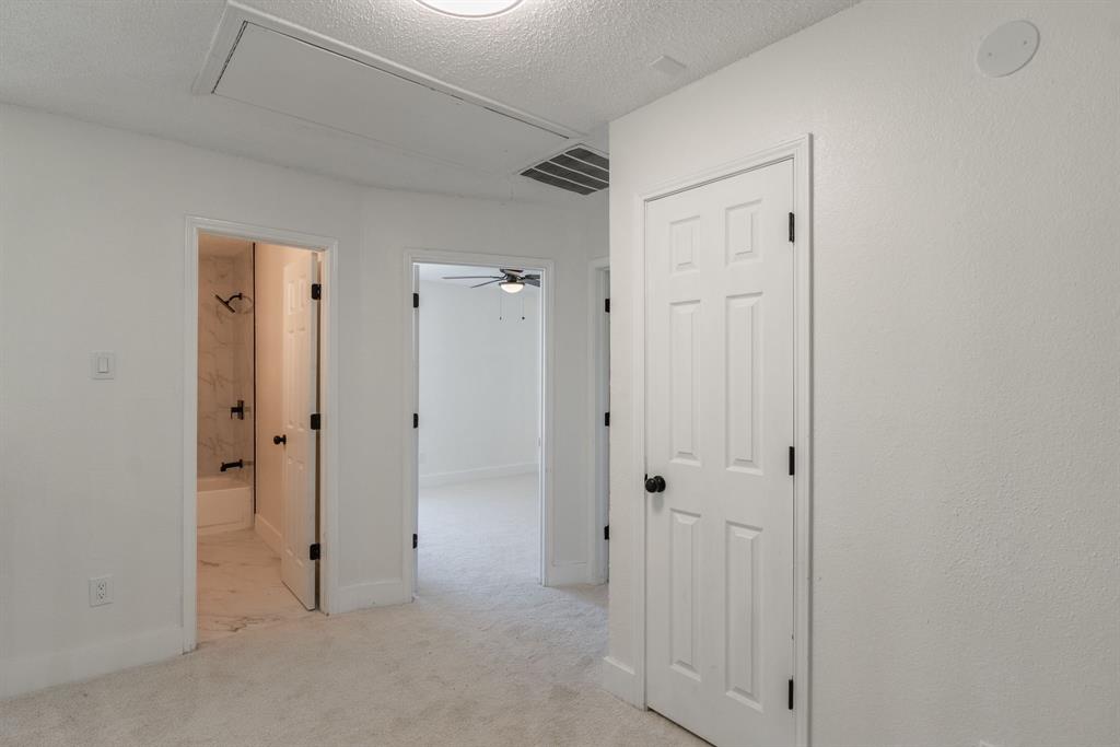 Carpeted hallway with white walls and trim, featuring a recessed ceiling access panel