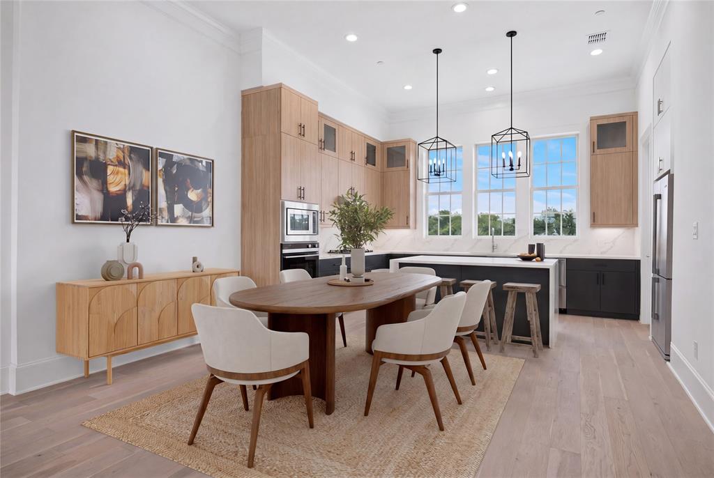 Open-concept kitchen and dining area featuring light wood-finish flooring, a kitchen island with seating, stainless steel appliances, and abundant natural light from multiple large windows