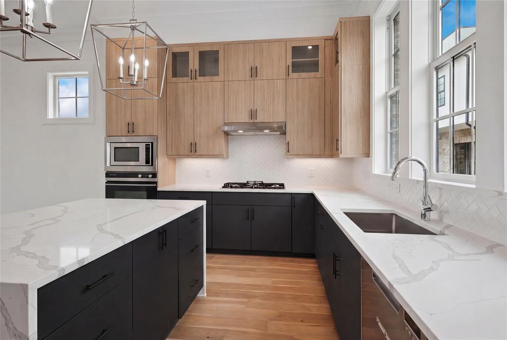Modern kitchen featuring light wood-finish upper cabinetry, dark lower cabinetry, and a large central island