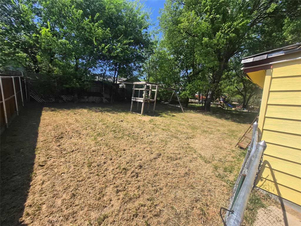 Expansive backyard featuring mature trees, a wooden privacy fence, and a chain-link fence