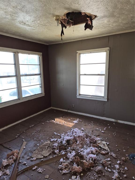 Room featuring two windows, textured ceiling, baseboard trim, and a ceiling light fixture