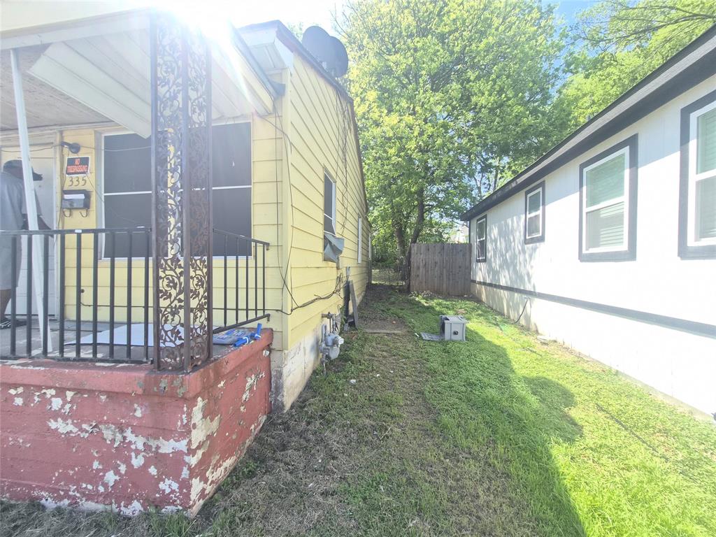 Yellow-sided residence with a covered front porch featuring decorative metalwork and a black railing