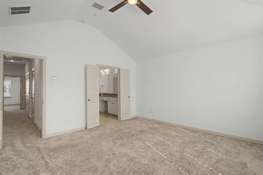 Spacious room featuring vaulted ceilings, light carpeting, and a ceiling fan