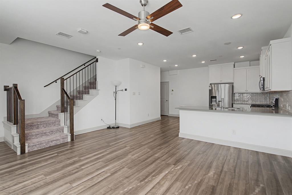 Open-concept living area with wood-finish flooring, a contemporary ceiling fan, and recessed lighting Open-concept living area with wood-finish flooring, a contemporary ceiling fan, and recessed lighting