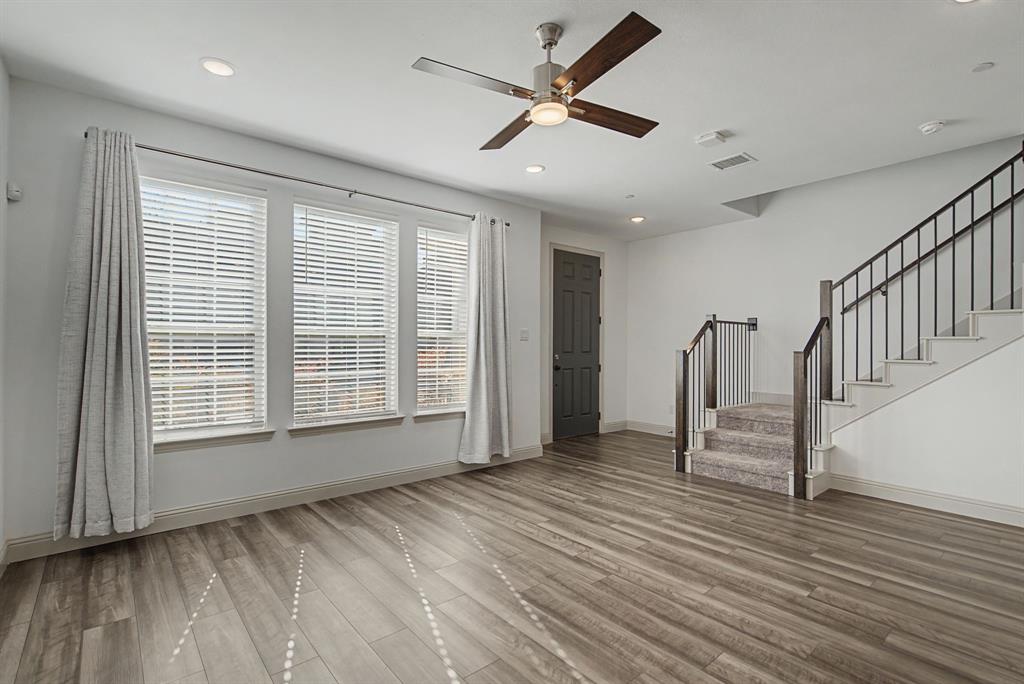 Spacious living area featuring wood-finish flooring, a contemporary ceiling fan, and recessed lighting Spacious living area featuring wood-finish flooring, a contemporary ceiling fan, and recessed lighting