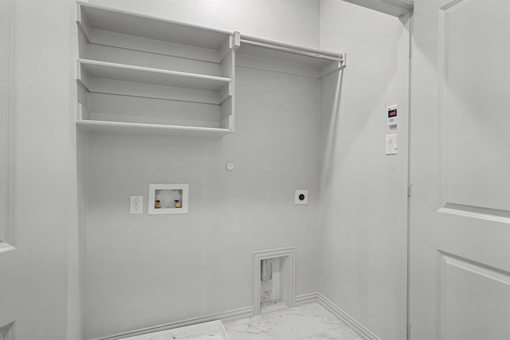 Utility room featuring built-in shelving, a clothes hanging rod, and marble-look tile flooring
