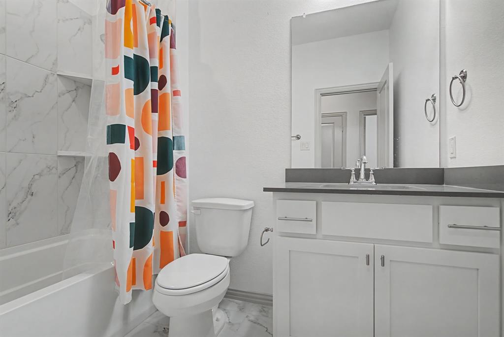 Bathroom featuring a white vanity with a dark countertop and undermount sink, a large wall mirror, and a toilet