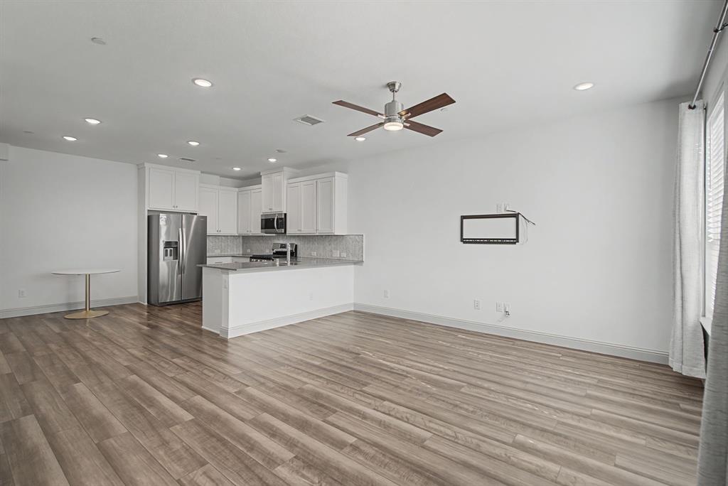 Open-concept living area featuring wood-finish flooring, recessed lighting, and a ceiling fan Open-concept living area featuring wood-finish flooring, recessed lighting, and a ceiling fan