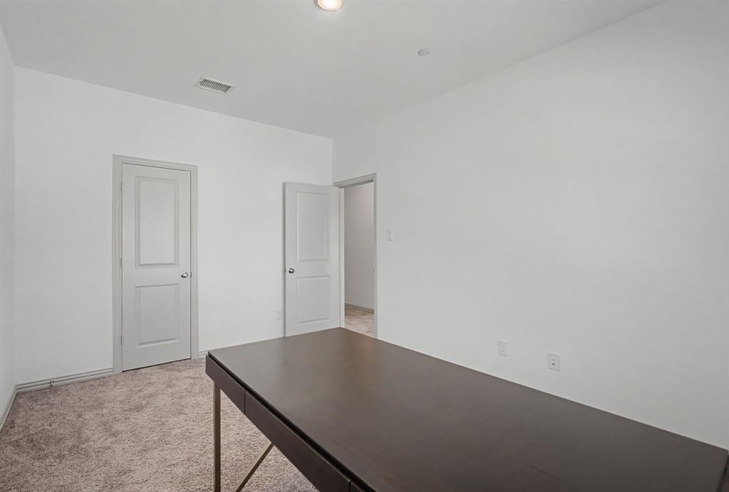 Interior room featuring light gray walls, two paneled interior doors, and textured carpet flooring