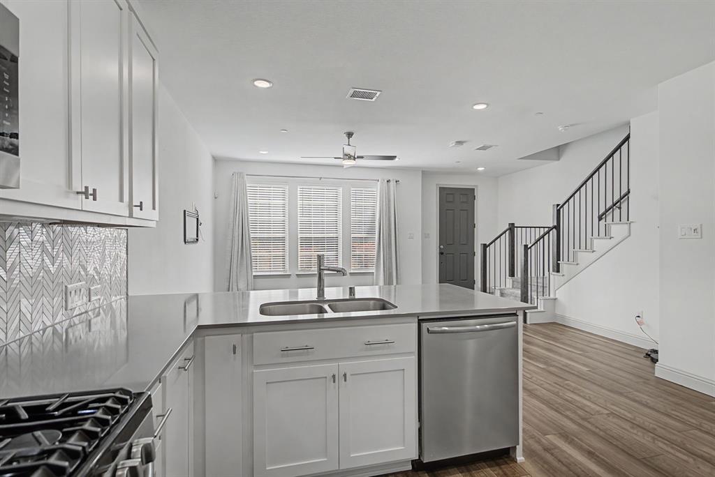 Contemporary kitchen island featuring a double-basin sink, stainless steel dishwasher, and quartz countertop