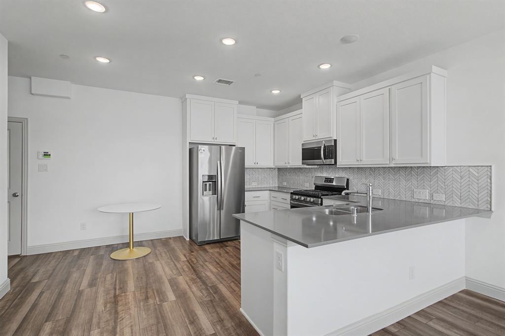 Modern kitchen featuring white cabinetry, stainless steel appliances, and a grey countertop Modern kitchen featuring white cabinetry, stainless steel appliances, and a grey countertop