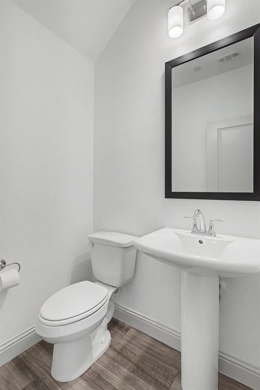 Pedestal sink with chrome faucet, framed mirror, and wood-finish flooring
