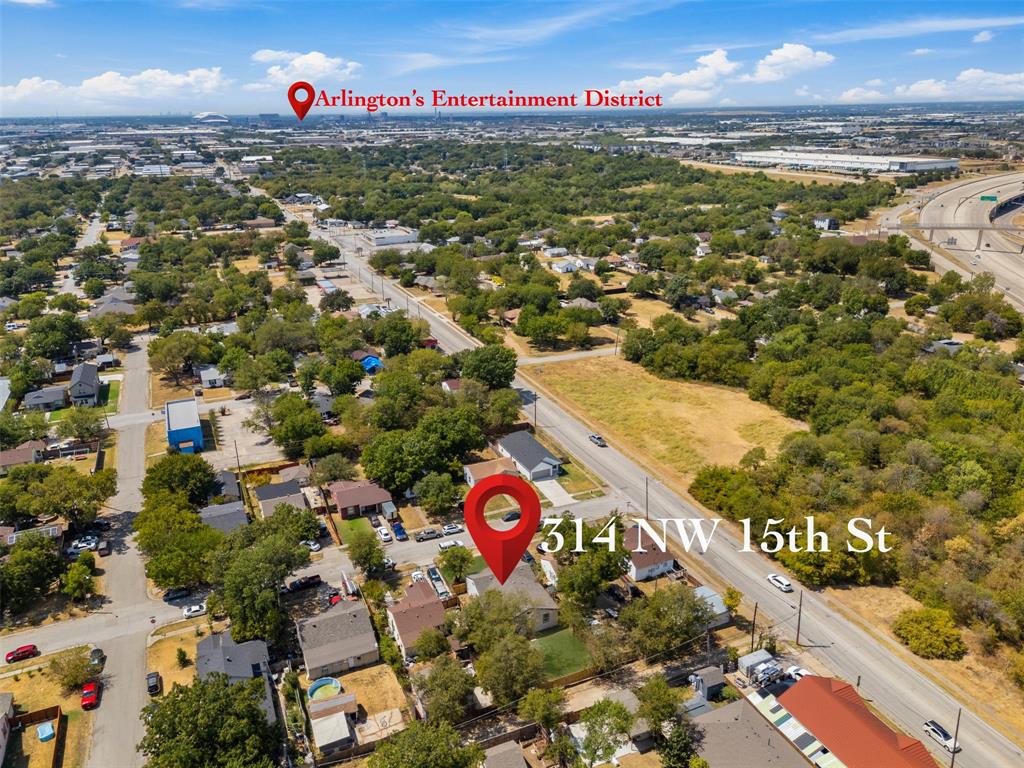 Aerial perspective of a residential neighborhood with mature trees and visible access to a multi-lane highway