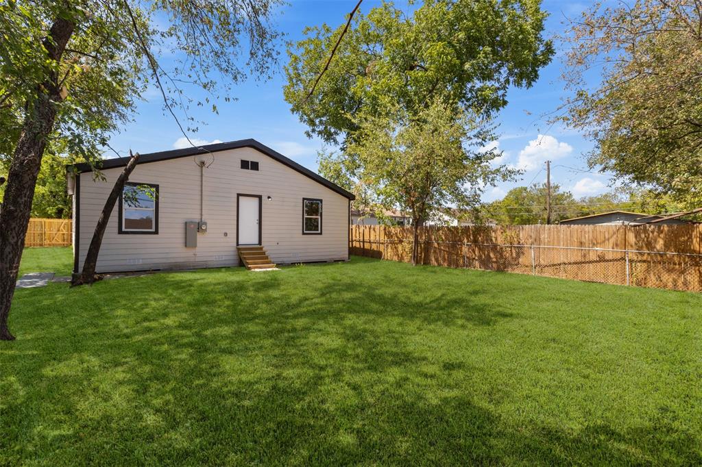 Expansive backyard with a manicured lawn, full perimeter wood fencing, and mature trees