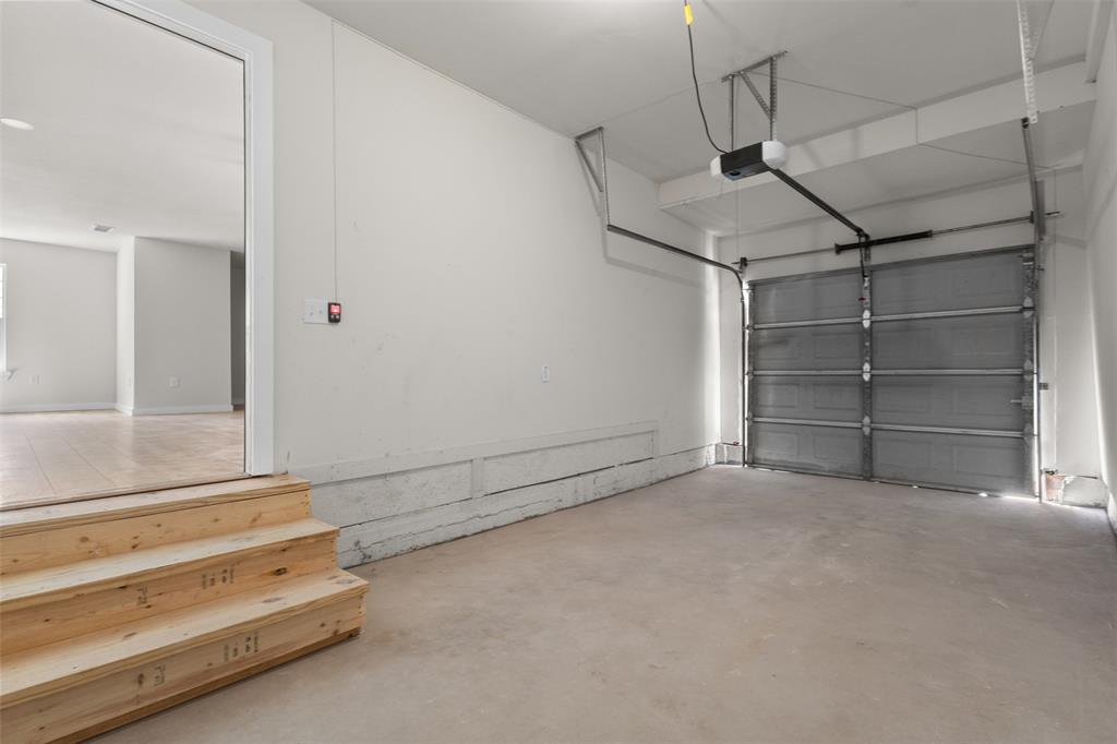 Attached garage with a roll-up door, automatic opener, and concrete flooring