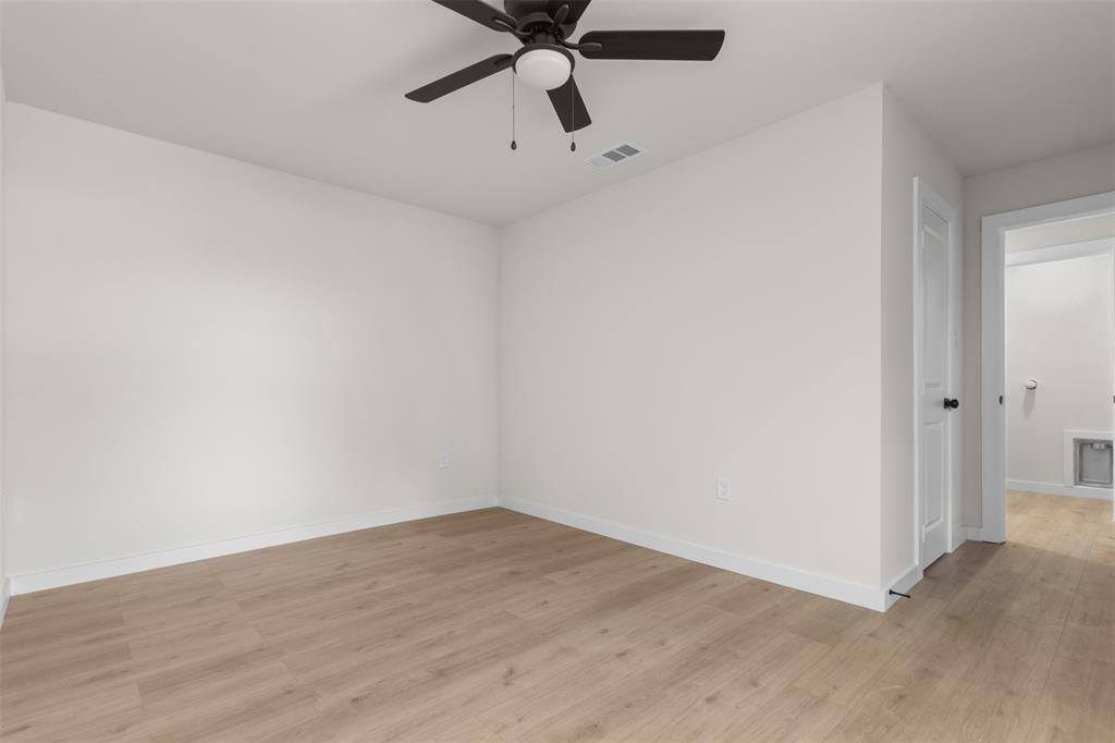 Wood-finish flooring, white walls, and a ceiling fan with light fixture